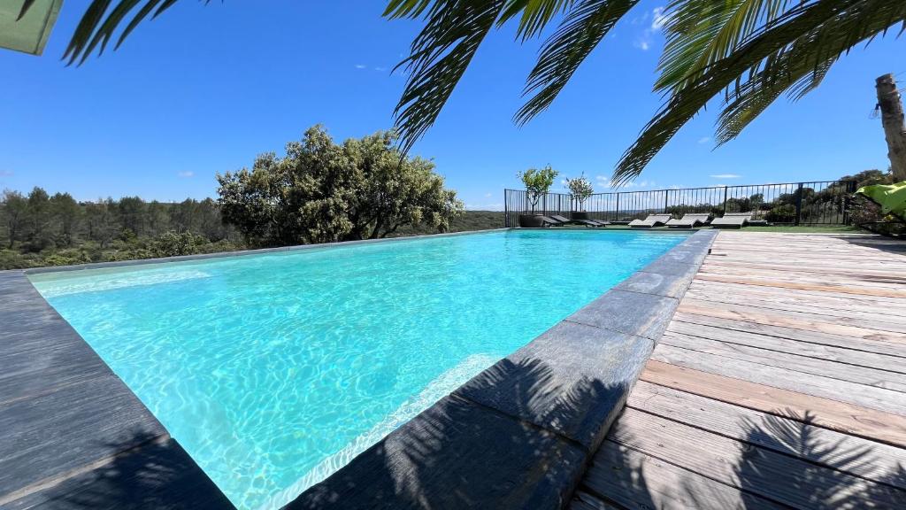 - une piscine avec une terrasse en bois et de l'eau bleue dans l'établissement Villa climatisée piscine billard ping-pong, à Saint-Maximin