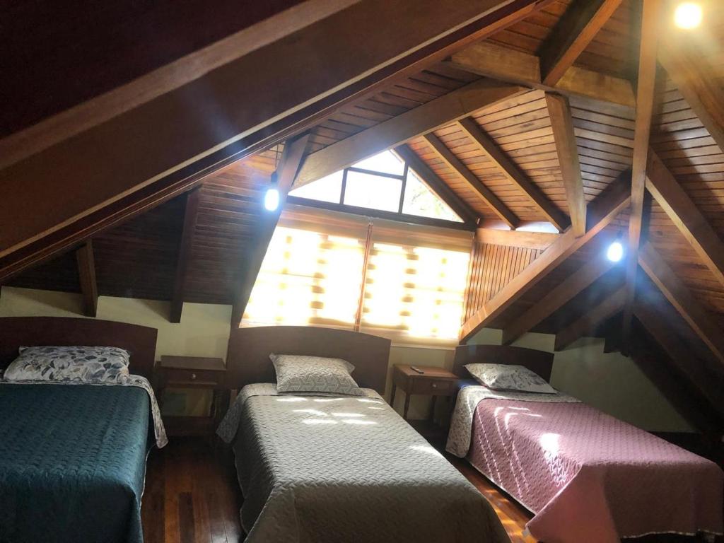 Cette chambre mansardée comprend 2 lits et une fenêtre. dans l'établissement CASA DE CAMPO HOSPEDAJe, à Ambato