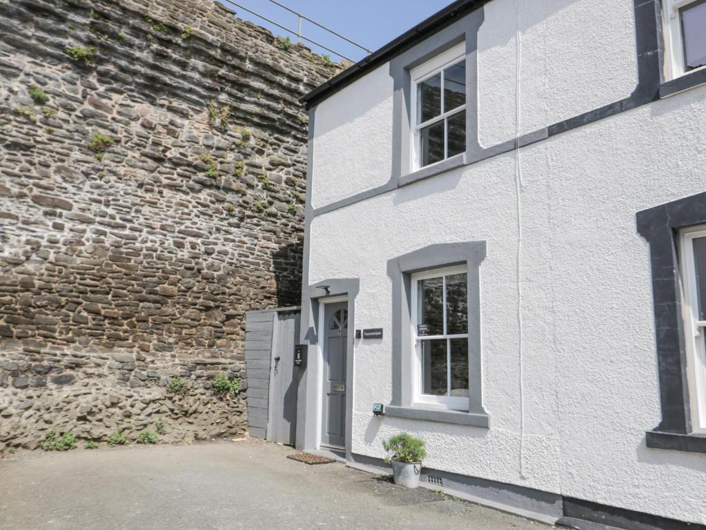 una casa bianca con una porta e un muro di mattoni di Havens End a Conwy
