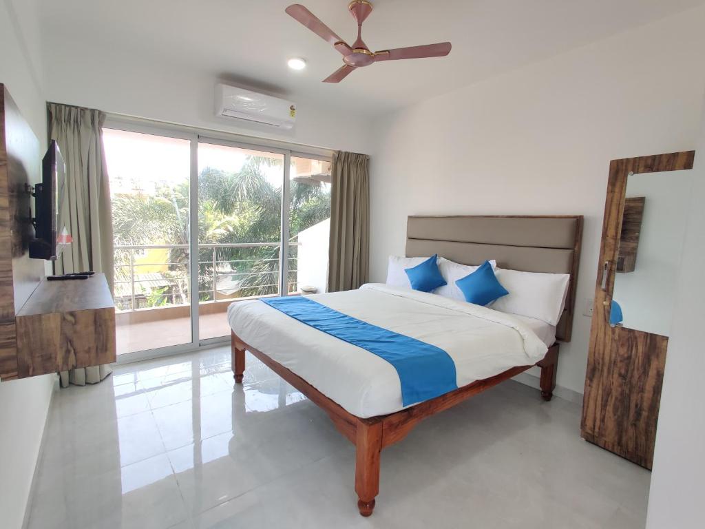 a bedroom with a bed with blue pillows and a window at Hotel MJ baga in Calangute