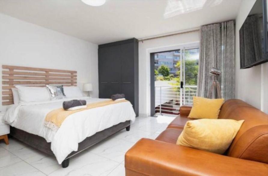 Un dormitorio con una cama grande y un sofá. en Trendy Green Point Retreat, en Ciudad del Cabo