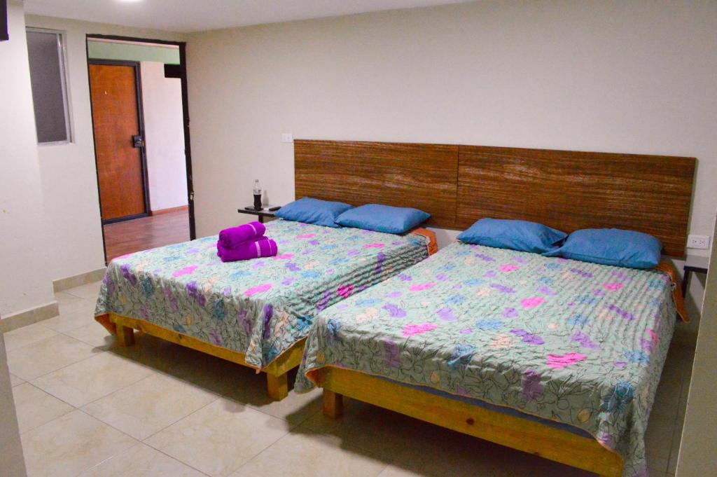 Posada Vacacional Brisas del Mar في مازاتلان: غرفة نوم بسريرين مع وسائد زرقاء وأرجوانية
