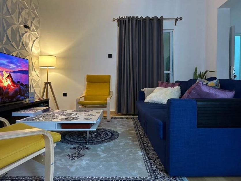 een woonkamer met een blauwe bank en een gele stoel bij Private room in Rayfied, Jos in Jos