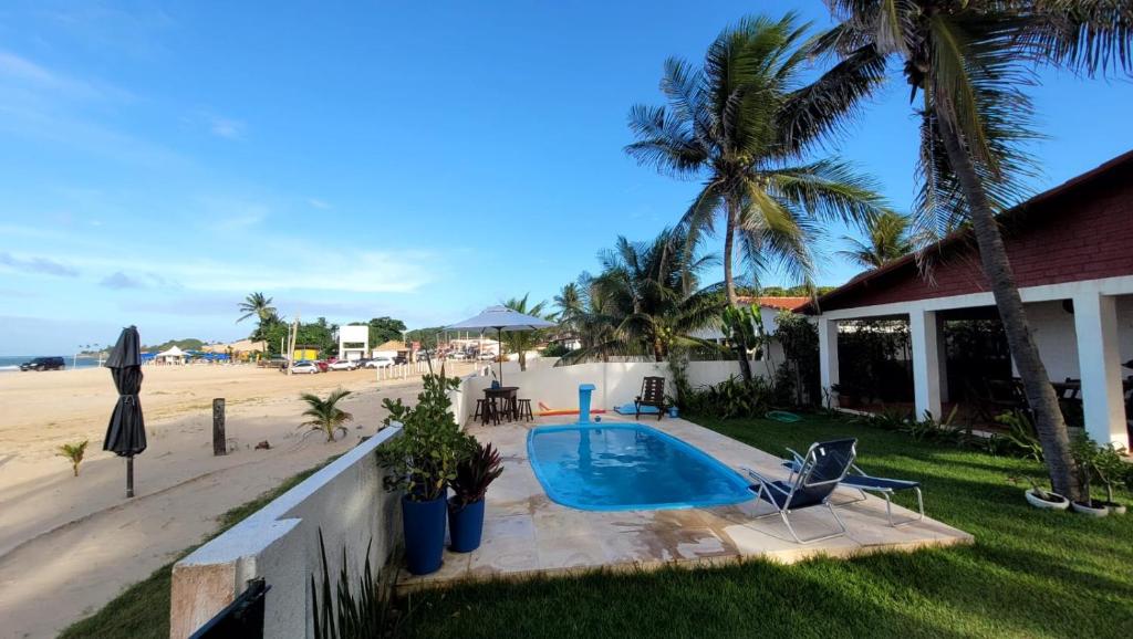 a house with a swimming pool next to a beach at Espaço Brilho do Sol Genipabu in Extremóz