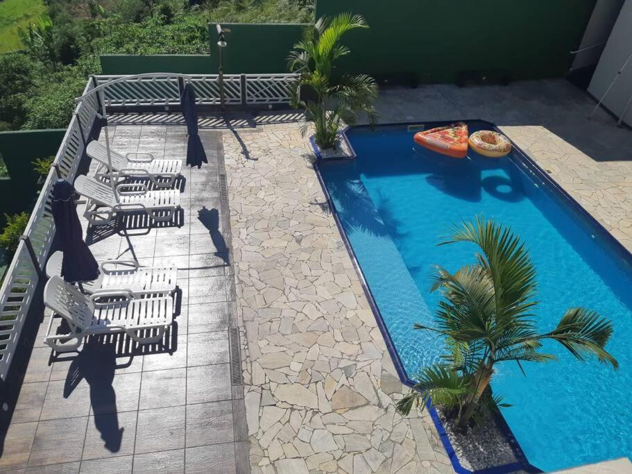 a swimming pool with chairs and a pizza in it at Sitio Arujá com Piscina Aquecida, Quadra e Vista Deslumbrante in Arujá