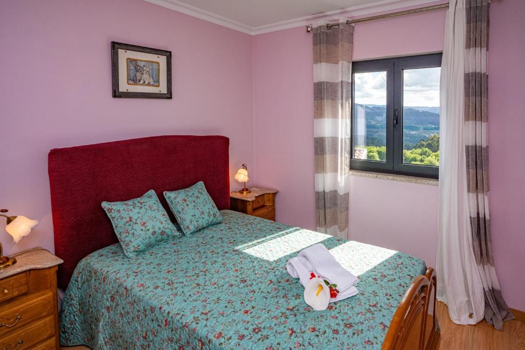1 dormitorio con 1 cama con colcha verde y ventana en CASA DA ROSARINHO - Casa de Campo Privada com Piscina - Arcos de Valdevez, en Arcos de Valdevez