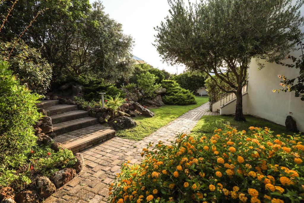 einen Garten mit einem Steinpfad und Blumen in der Unterkunft Il Borgo BagaBaga - Exclusive Country Retreat in Castelsardo