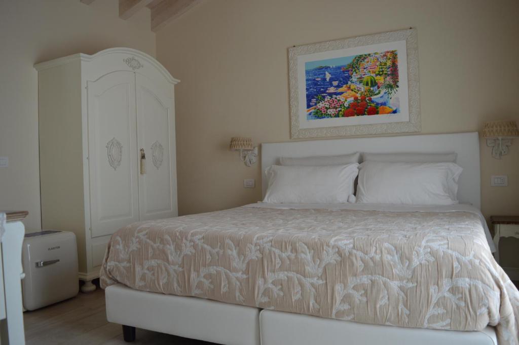 um quarto com uma cama branca e uma pintura na parede em B&B La Fiaba em Sirmione