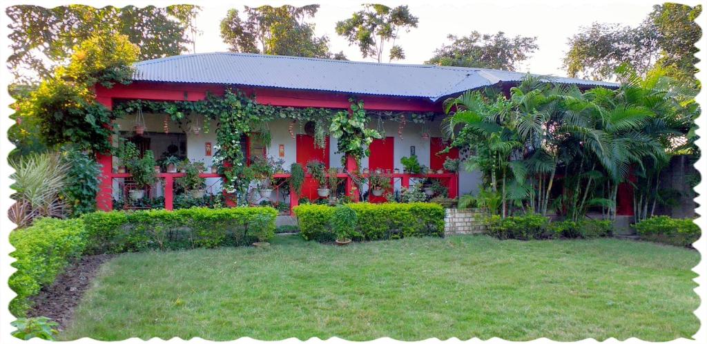 uma casa vermelha e branca com um quintal em Atmaja The Cottage Garden Home Stay Malda Under Tourism Department Government of West Bengal em Māldah
