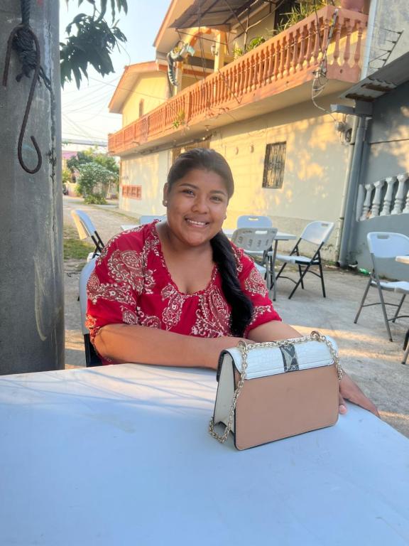 una mujer sentada en una mesa con un bolso en villa en palma real, en La Ceiba
