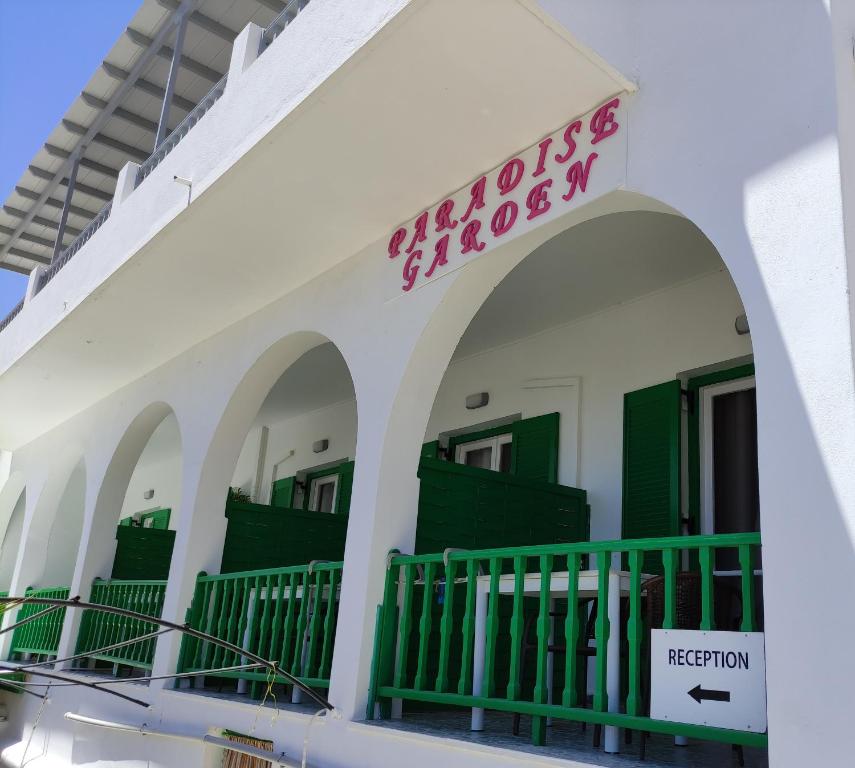 een gebouw met groene deuren en een bord erop bij Paradise Garden Paros in Piso Livadi