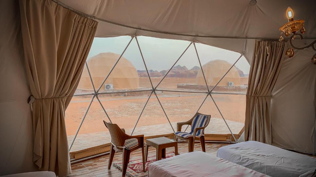 a room with a window with two beds and chairs at Sama Rum Luxury Camp in Wadi Rum