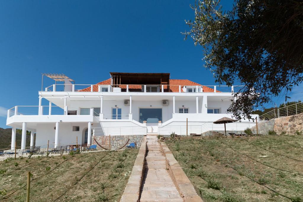 una grande casa bianca in cima a una collina di Poseidon Apartments and Villas by the Sea a Sounio