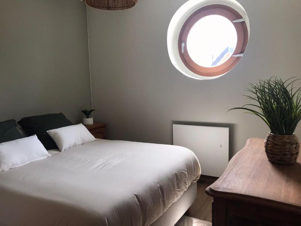 a bedroom with a bed and a round window at Gîte du Moulin Pidoux in Hallines