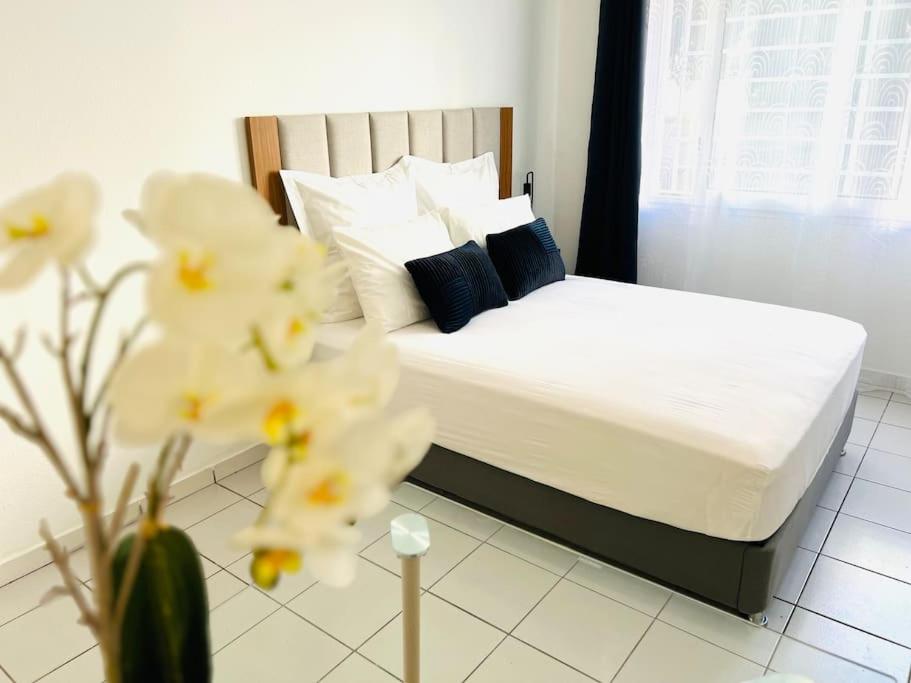 - une chambre avec un lit doté de draps blancs et d'oreillers bleus dans l'établissement T1 - Le Tuit-Tuit 5* - 9' centre ville, à Saint-Denis