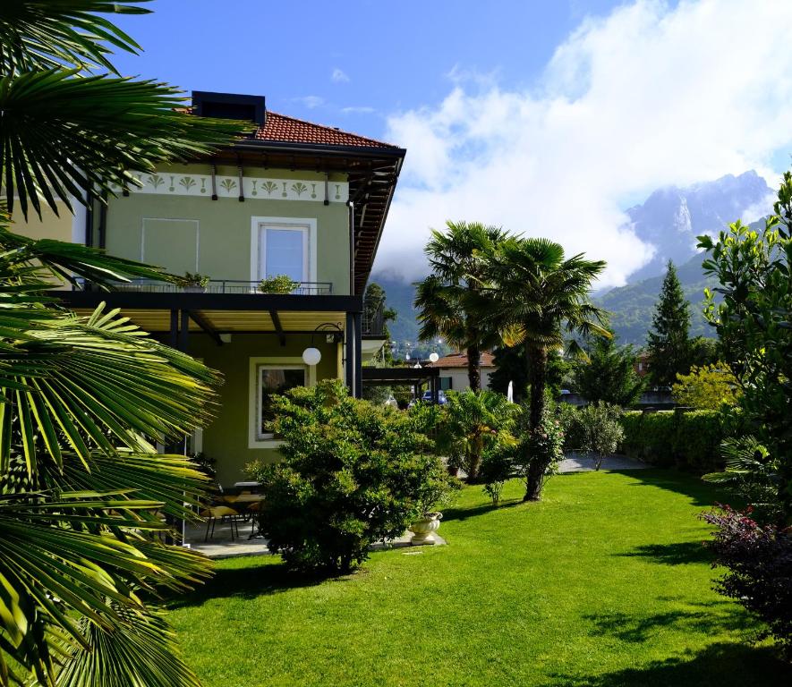 una casa con un giardino verde con palme di Residenza Laurum a Mandello del Lario