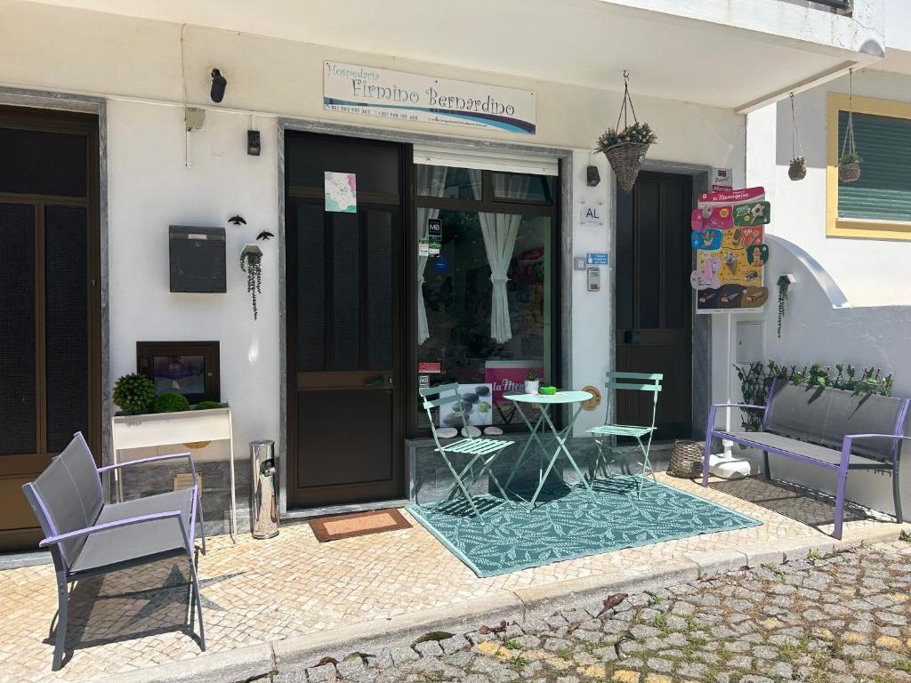 patio con sedie e tavolo di fronte a un edificio di Hospedaria Firmino Bernardino a Odeceixe