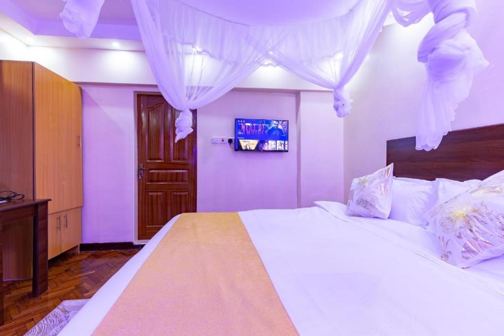 a bedroom with a large white bed with purple walls at Markson Hotel Kilimani in Nairobi