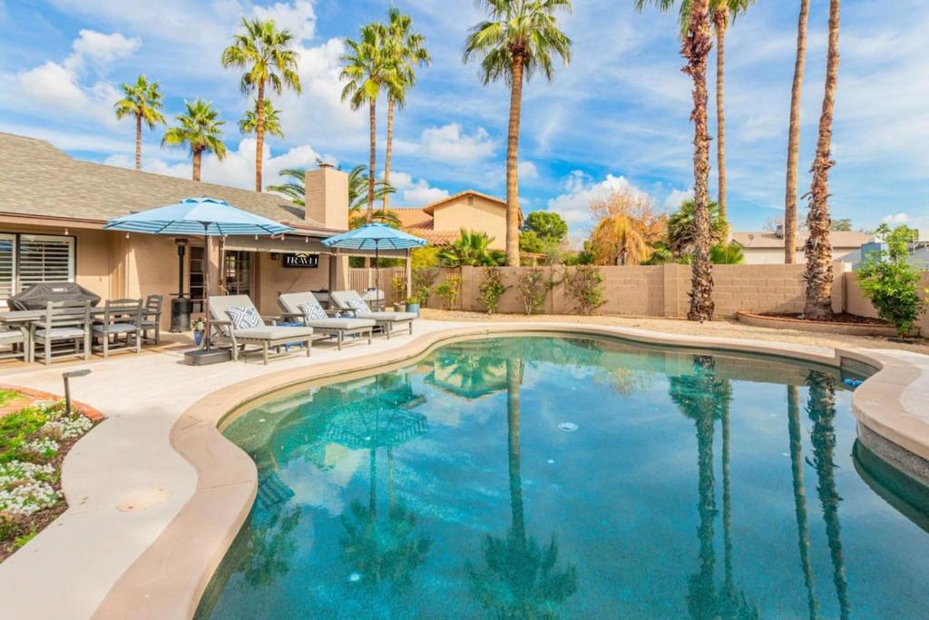 una piscina con palmeras y una casa en Greenway Park Oasis-Htd Pool-Putt-Firepit en Phoenix