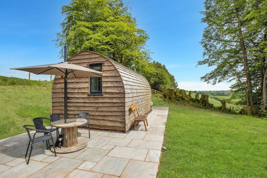 a wooden cabin with a table and chairs and an umbrella at Little House in the Big Woods Brendon Hill in Watchet