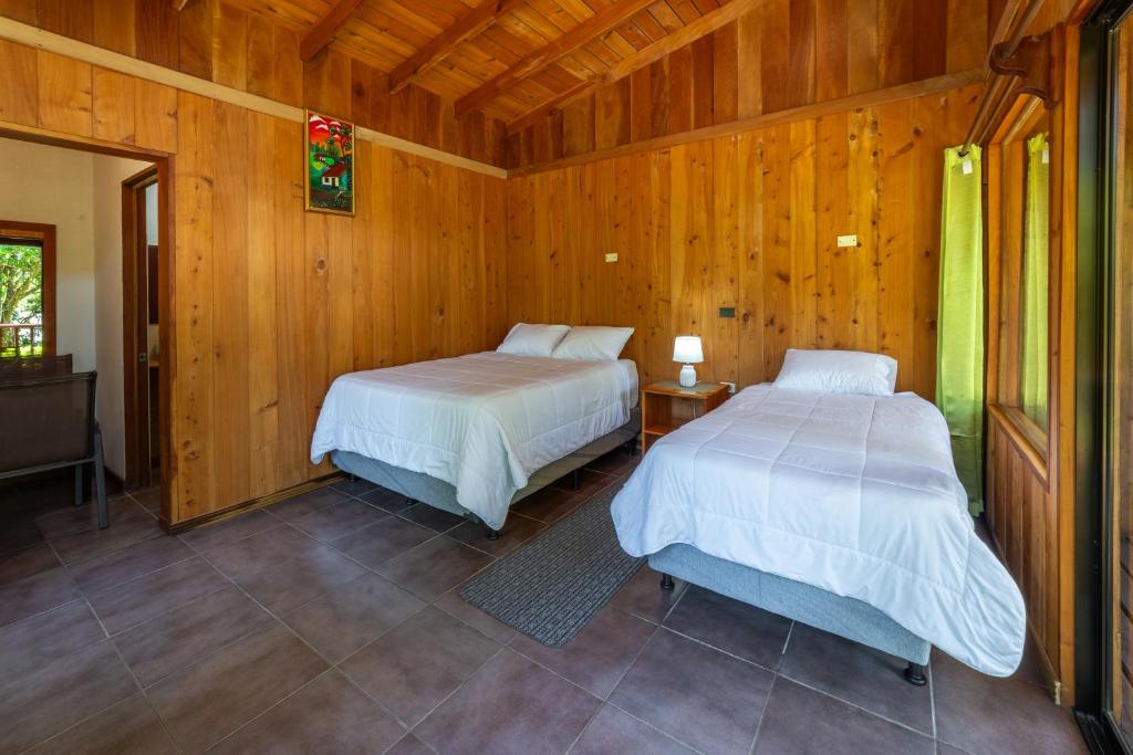 2 camas en una habitación con paredes de madera en Campo Verde B&B - Monteverde Costa Rica en Monteverde Costa Rica