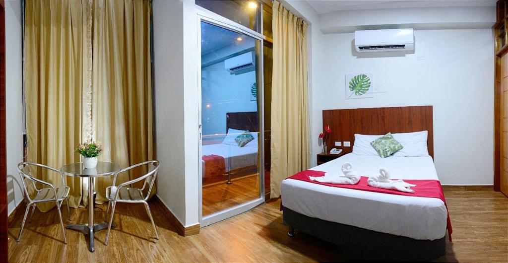una camera d'albergo con letto, tavolo e sedie di HOTEL LA PALMERA DE ORO a Tarapoto