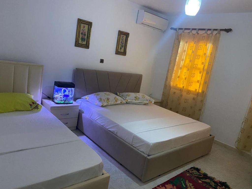 1 dormitorio con 2 camas y ventana en N'Eden Hostel en Berat
