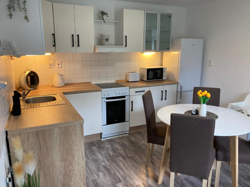 a kitchen with white cabinets and a table and a table and chairs at Apartmán Lipno 1 in Lipno nad Vltavou