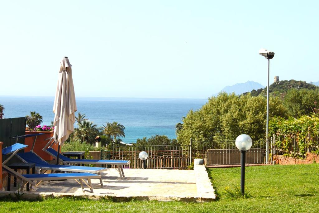 a patio with chairs and an umbrella and the ocean at Arbatax Le Terrazze sul Mare in Àrbatax