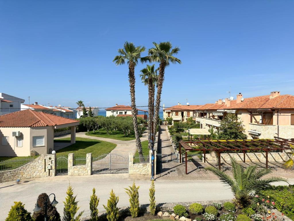 un parco con palme, panchine e case di Luxury Seaside Apt In Pefkochori Featuring Pool a Pefkohori