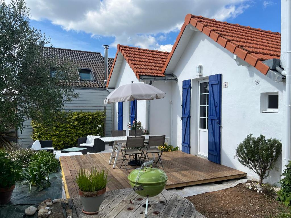 une maison blanche dotée d'une terrasse en bois avec un parasol dans l'établissement Maison typique - Crève-coeur, à La Bernerie-en-Retz