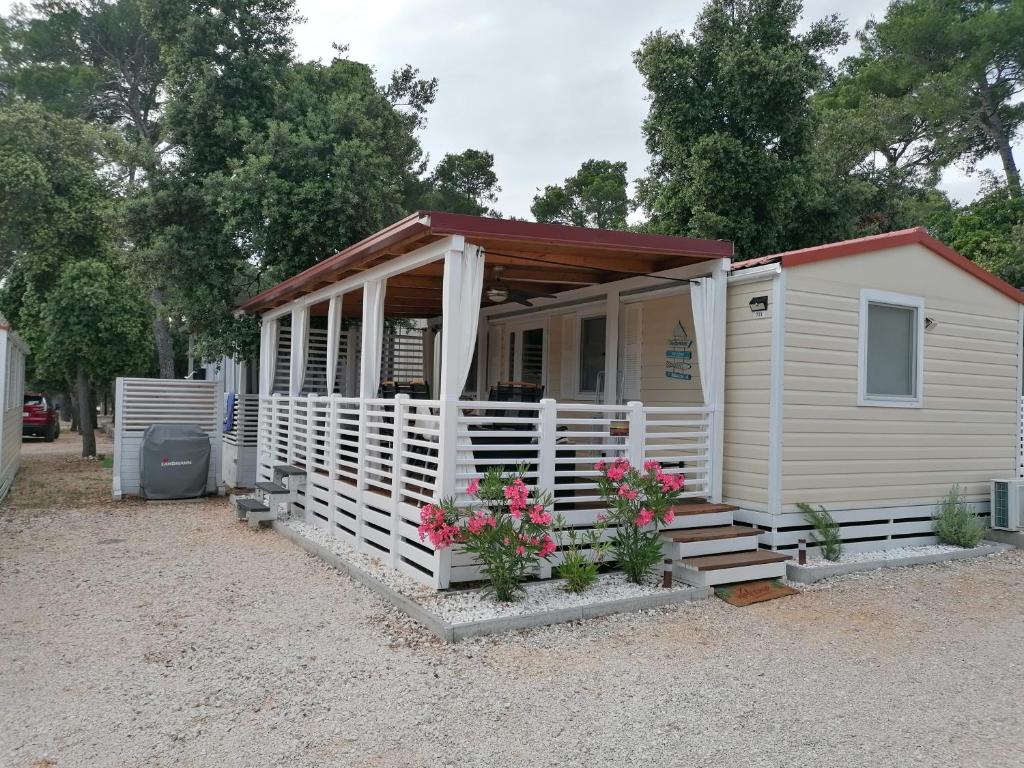 ein kleines weißes Haus mit einer Veranda und Blumen in der Unterkunft SweetHome in Biograd na Moru