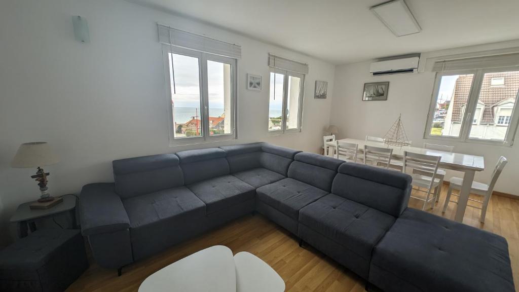 ein Wohnzimmer mit einem blauen Sofa und einem Tisch in der Unterkunft Coastal Breeze Apartment - Equihen-Plage in Équihen-Plage