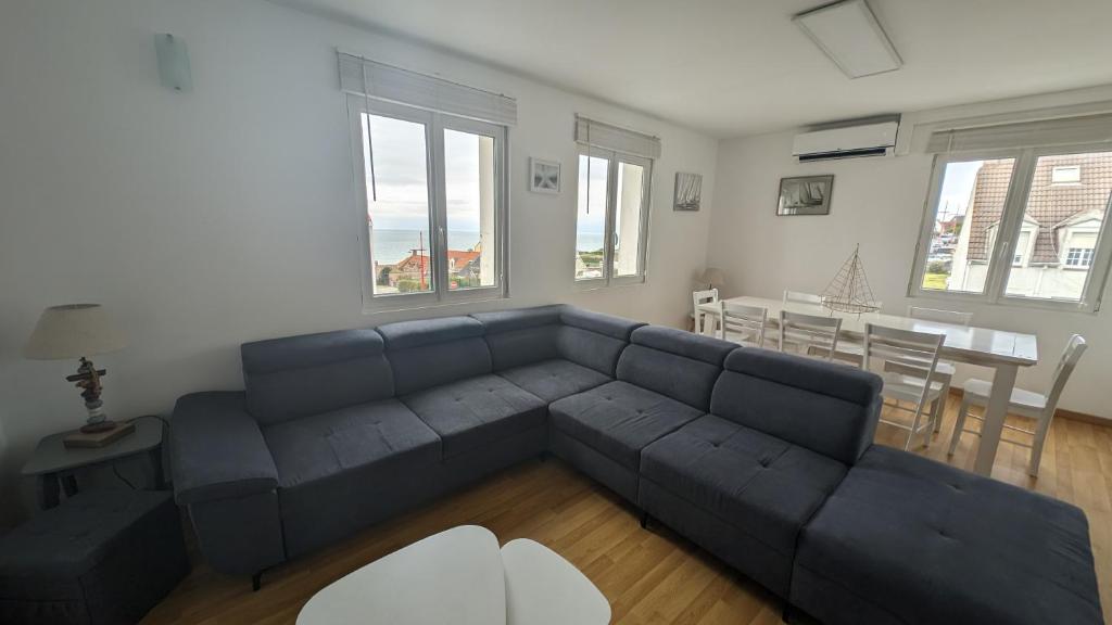 un salon avec un canapé bleu et une table dans l'établissement Coastal Breeze Apartment - Equihen-Plage, à Équihen-Plage
