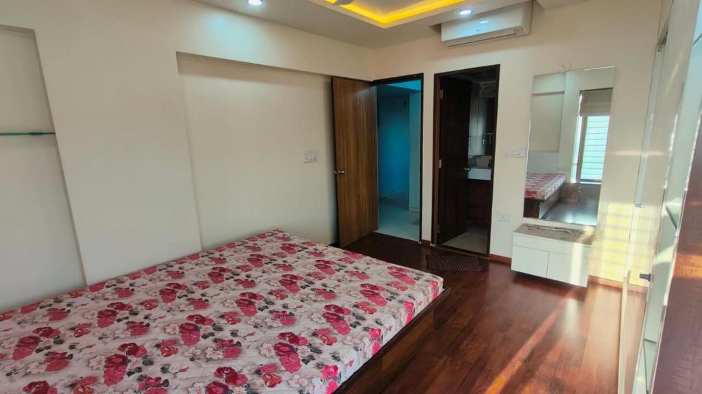 um quarto com uma cama com flores vermelhas em The ten - 2 rooms in 3bhk apartment em Pune