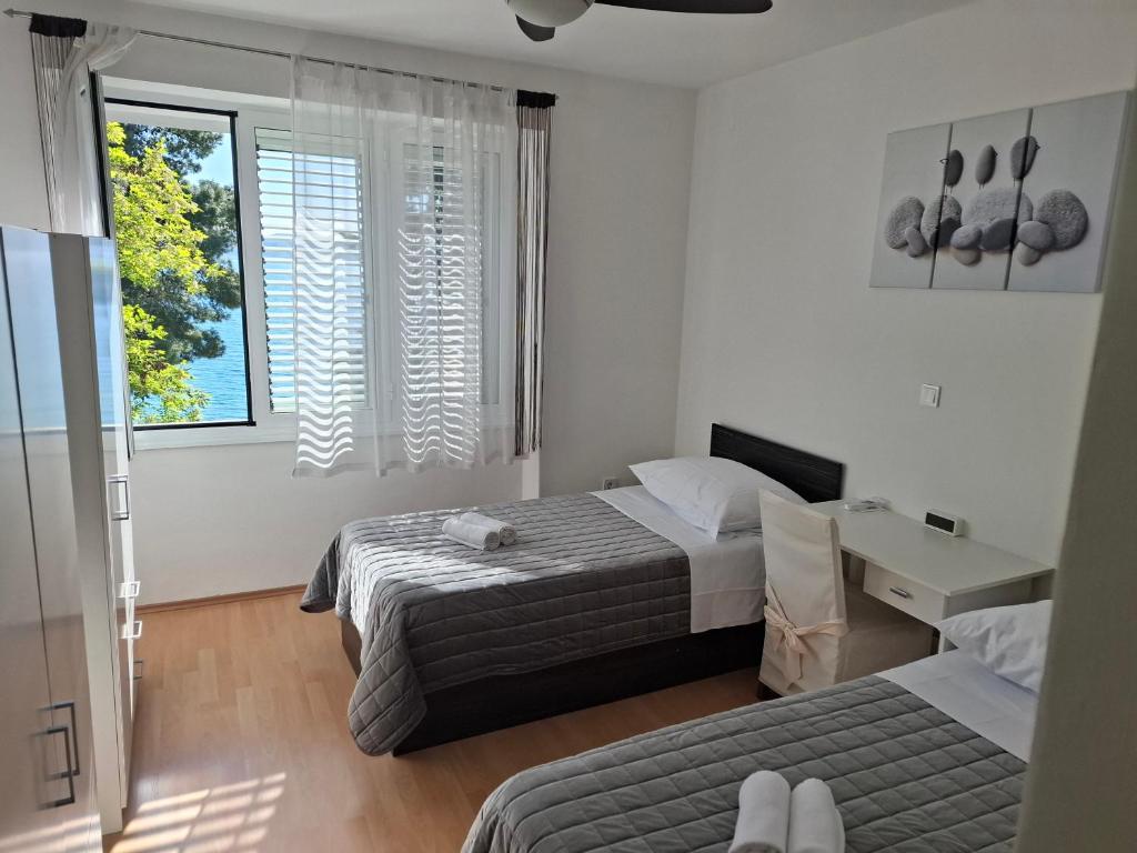 1 Schlafzimmer mit 2 Betten, einem Schreibtisch und einem Fenster in der Unterkunft Barka Zadar in Zadar