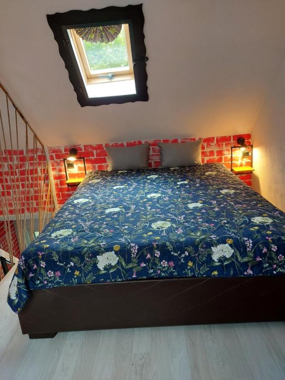 sypialnia z łóżkiem z niebieską kołdrą i oknem w obiekcie Przylesie Dom Turystyczny w Ostródzie