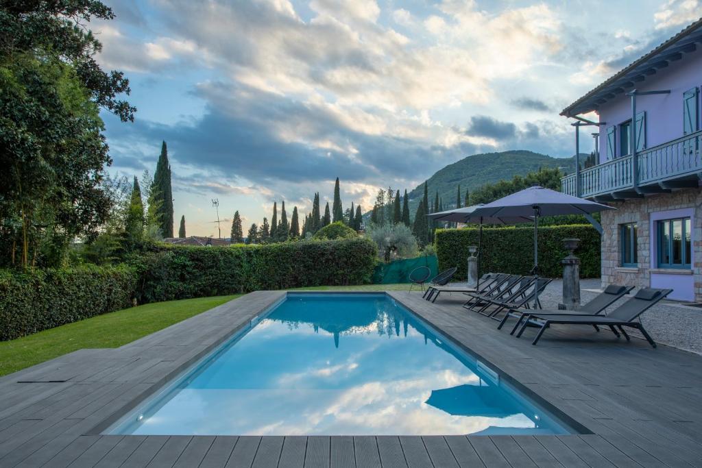 a swimming pool in a yard with two chairs and an umbrella at Villa Laura in Gardone Riviera