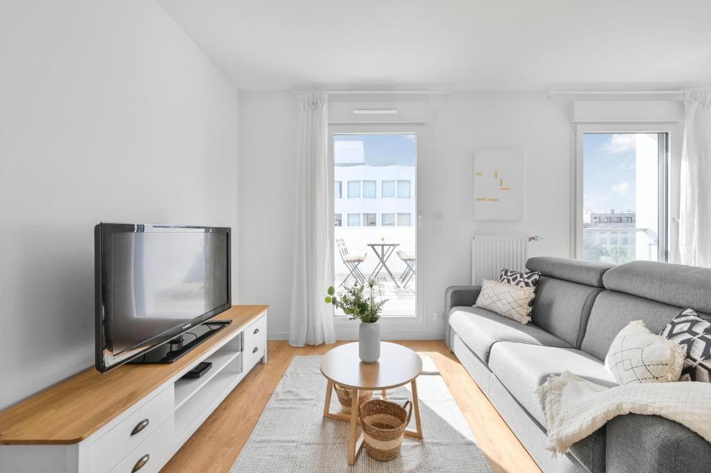 een woonkamer met een bank en een tv bij Appartement Chic au Coeur de Massy in Massy