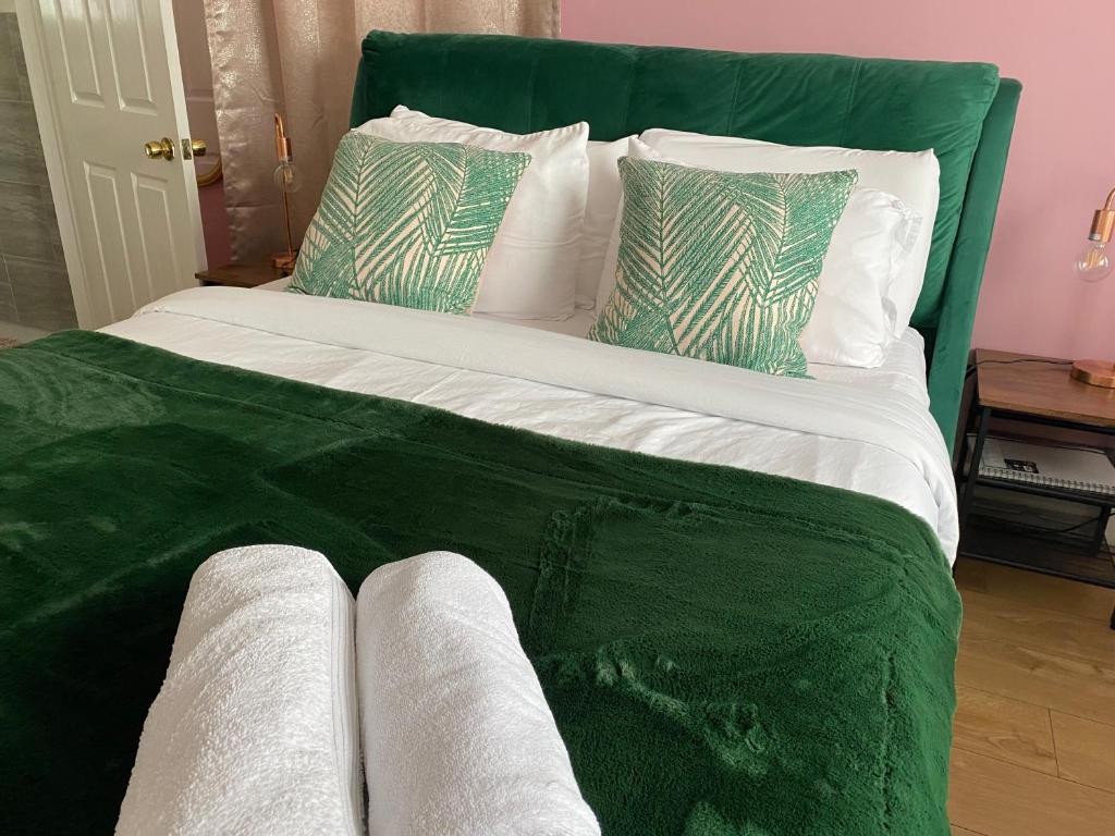 a large bed with green sheets and pillows at The Lily Pad in Corfe Mullen