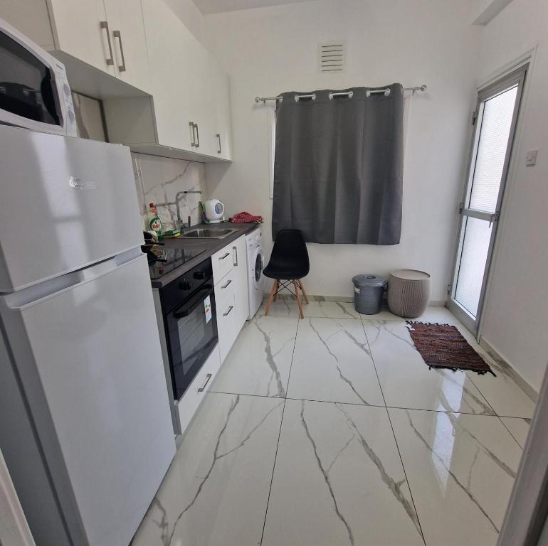 Il comprend une cuisine dotée d'un sol en marbre blanc et d'un réfrigérateur. dans l'établissement Cozy 1 bedroom apartment Larnaca city-center F, à Larnaka
