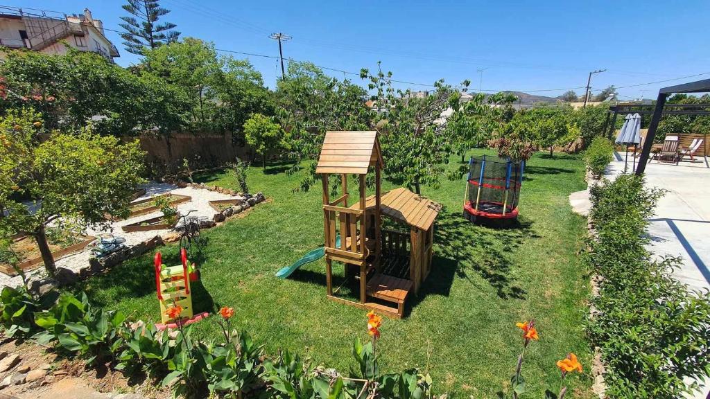 a garden with a play set in the grass at Anasa Residence - The Farm house in Varípetron