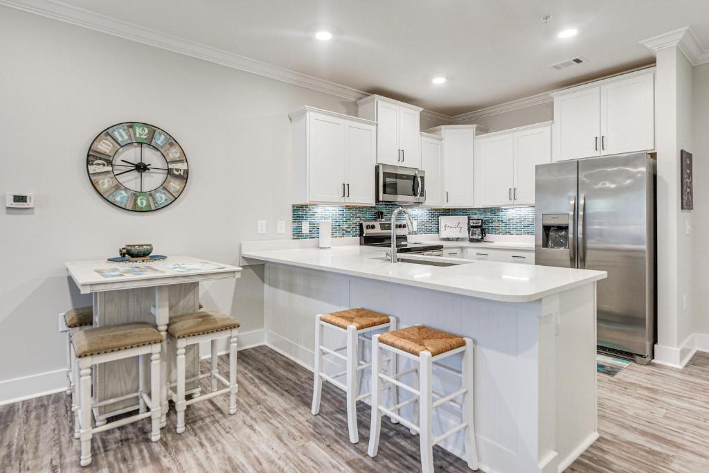 a kitchen with white cabinets and a counter with stools at Gorgeous Calabash Condo with Balcony and Pool Access! in Calabash
