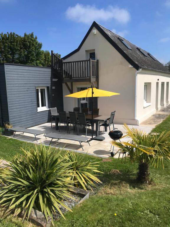 un patio avec une table, des chaises et un parasol jaune dans l'établissement L’Augustine, maison contemporaine à la campagne !, au Tilleul