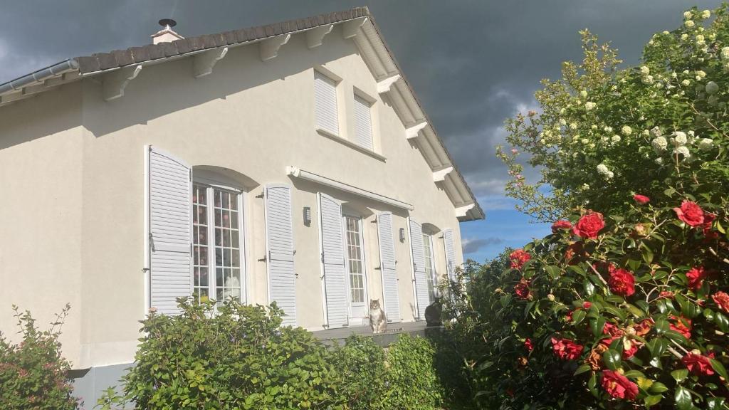 Casa blanca con persianas blancas y rosas rojas en A 15 mn ouest Caen, en Noyers-Bocage