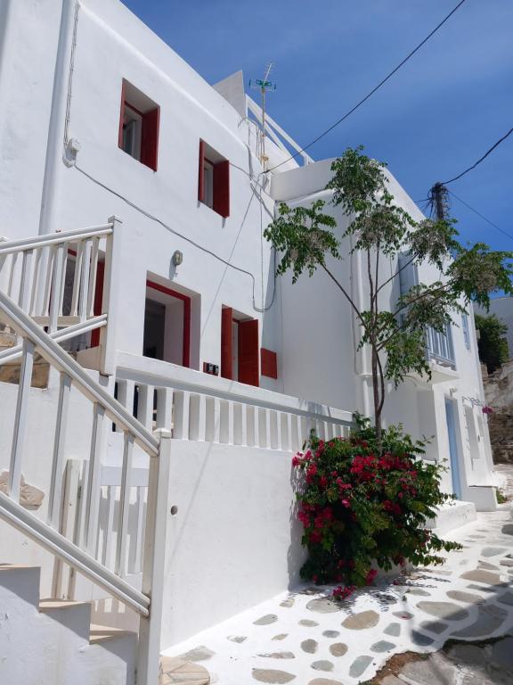 a white house with red windows and a plant at Alex oldtown sea view rooms and appartments in Mýkonos City