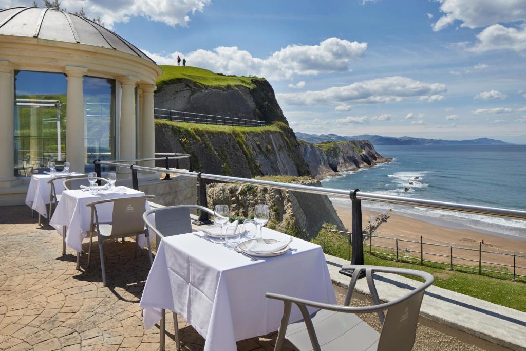 un restaurante con mesas y vistas al océano en Hotel & Talasoterapia Zelai - HSS00653, en Zumaia