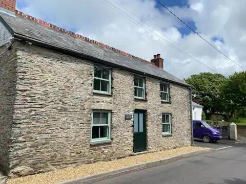 a brick building with a blue car parked next to it at Tregue Cottage in Camelford