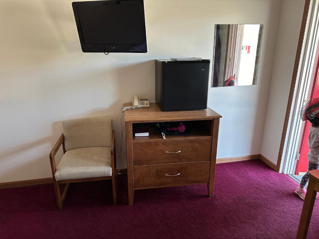 um quarto com uma secretária, uma televisão e uma cadeira em VISTA VILLA MOTEL em Ludington