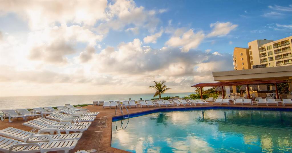 a swimming pool with lounge chairs and the ocean at Beach Front Place in Cancún